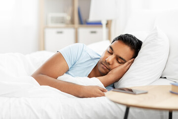 people, bedtime and rest concept - indian man sleeping in bed at home