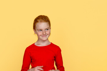 A young funny  girl with red hair  looks sideaways with a sly look against  blue background