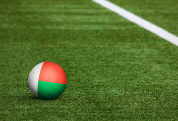 Fototapeta na wymiar Madagascar flag on ball at soccer field background. National football theme on green grass. Sports competition concept.