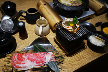 Wooden table fulled of vegetables, Kani miso (grilled Crab meat), Sliced Wagyu beef and pork, rice, raw egg and dipping sauce- Sukiyaki (Japanese hot pot)