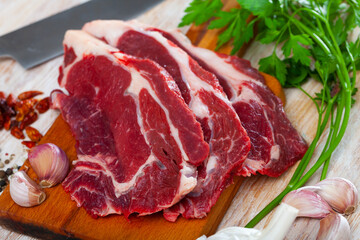 Sliced raw veal steak with black pepper on wooden table, ingredients for food preparation