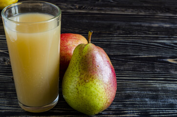 a glass of pear juice and juicy pears on a dark wooden background close up copy space