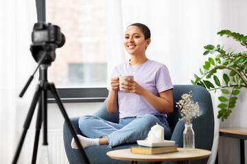 blogging, videoblog and people concept - happy smiling african american female video blogger with camera and cup of coffee videoblogging at home