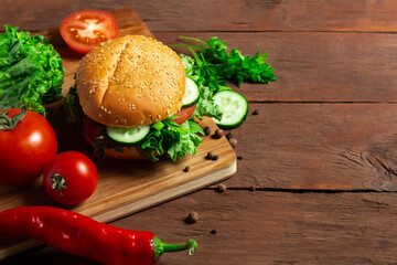 Fresh vegetarian burger on a dark wooden background. Salad, vegetables