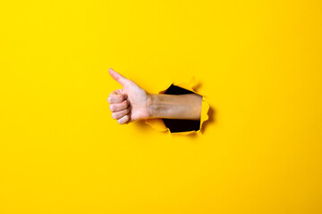 Male hand showing thumb up gesture, everything is ok, class on yellow background.