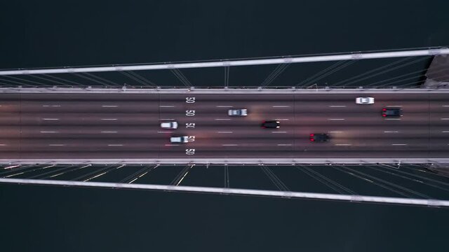4K aerial overhead horizontal video of rush hour traffic at Bay Bridge in direction of downtown San Francisco. Modern suspension bridge above the dark green waters is illuminated in the dark, USA