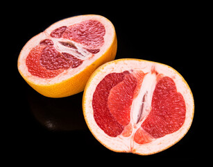 two halves of grapefruit on a black plate