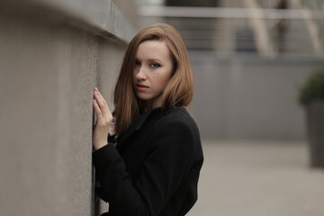 The girl in black coat. Beautiful emotional young girl in the city. Shawl or handkerchief on a person. 