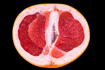 half of red grapefruit on a black plate