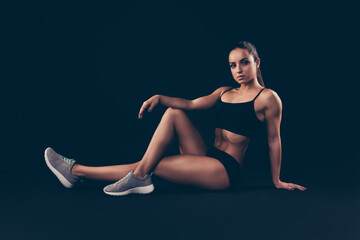 Portrait of her she nice-looking attractive sportive adorable content strong serious lady sitting on floor warming limbering up isolated over black background
