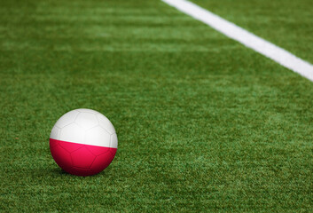 Poland flag on ball at soccer field background. National football theme on green grass. Sports competition concept.