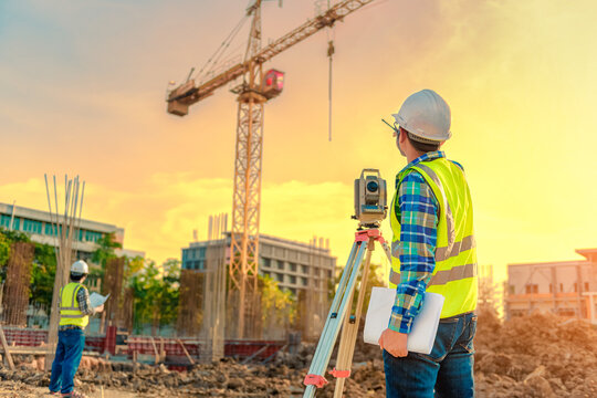 Surveying engineers are working together using theodolite on the construction site.