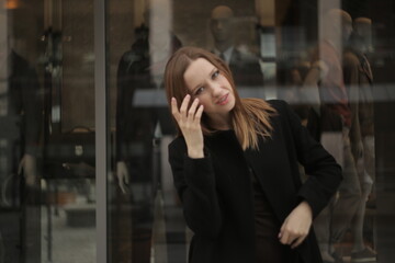 The girl in black coat. Beautiful emotional young girl in the city. Shawl or handkerchief on a person. 