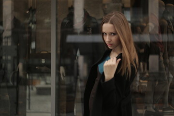 Fototapeta premium The girl in black coat. Beautiful emotional young girl in the city. Shawl or handkerchief on a person. 