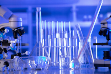 Coronavirus pandemic theme. Science research concerning fast covid tests and anti-covid vaccine. Beakers, microscope and test tubes on blue background.