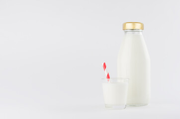 White milk, dairy product in glass bottle  mock up with glass, red straped straw in soft light white background.
