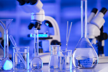 Coronavirus pandemic theme. Science research concerning fast covid tests and anti-covid vaccine. Beakers, microscope and test tubes on blue background.