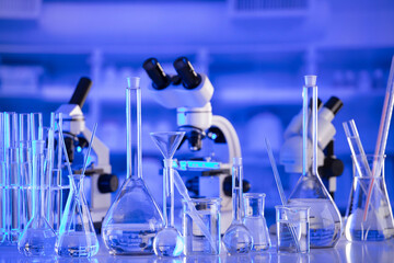 Coronavirus pandemic theme. Science research concerning fast covid tests and anti-covid vaccine. Beakers, microscope and test tubes on blue background.