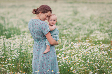 Mother and child in a chamomile field in summer. Maternal love tenderness care. Motherhood is...