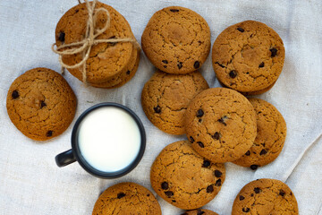 Homemade oatmeal cookies with chocolate drops and a cup of fresh milk. View from above.