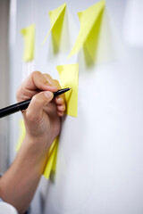 Young millennial business woman thinking and writing creative ideas to stickers on whiteboard. Startup planning. Creative team working on strategy