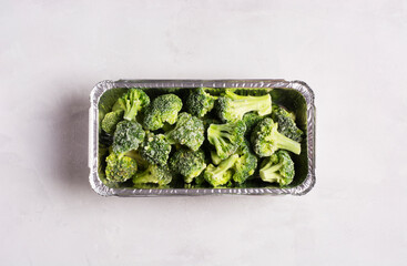 Frozen broccoli cabbage on gray surface, flat lay, healthy food concept. Horizontal orientation.