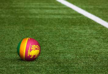 Sri Lanka flag on ball at soccer field background. National football theme on green grass. Sports competition concept.