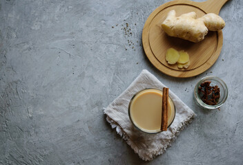 Masala tea in a glass cup on a linen napkin. The background is gray. Image with copy space, top view, horizontal orientation.