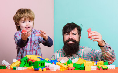 Happy family. Father and son have fun with bricks. Child development and upbringing. Bearded hipster and boy play together. Dad and child build of plastic blocks. Happy childhood. Child care concept