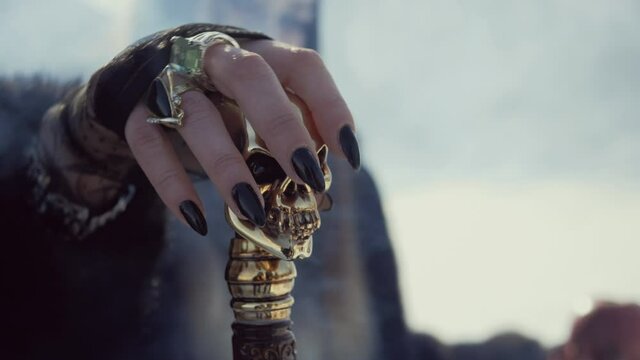 A laughing witch with a black crown on her head and a staff in her hands