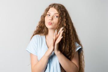 Naklejka premium Photo of thoughtful European young woman with curly long hair looks with dreamy expression aside. Isolated over white background.