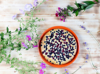 Berry pie on plate on wooden background with flowers