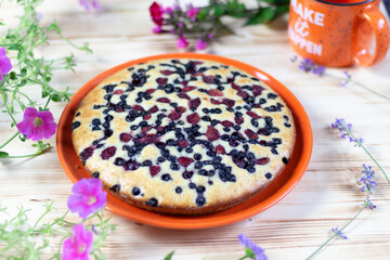 Fototapeta na wymiar Blachberry pie on plate on wooden background with flowers and cup
