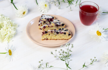 Slices of Berry pie on plate on wooden background with flowers and juice glass