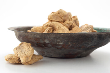 Ginger grains in white background and old copper bowl