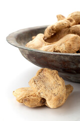Ginger grains in white background and old copper bowl