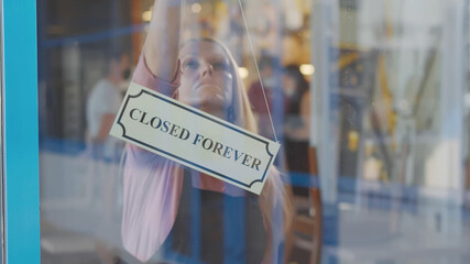 Senior woman business owner bankrupt hanging up sign with inscription closed forever