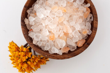 Salt grains in white background and wooden presentation bowl