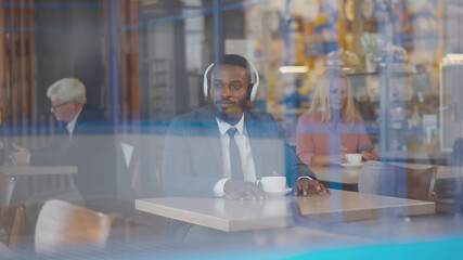 Handsome african businessman relaxing listening to music with headphones and coffee in cafe.