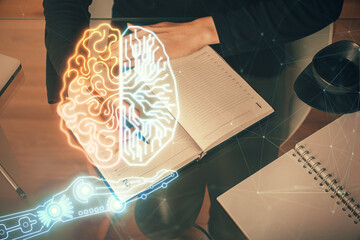 Double exposure of writing hand on background with brain hologram. Concept of learning.