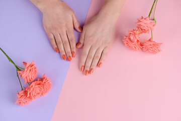 Simple manicure and groomed hands. Nails painted with pinkish coral lacquer