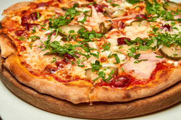 Fresh pizza with bacon, tomatoes, pickles and cheese on a light background. Close-up, selective focus