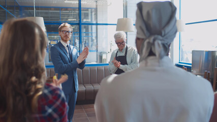 Smiling cafe owner introducing new hired employee at morning briefing