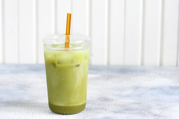 Matcha green tea ice latte with almond milk in a glass. Grey stone background.