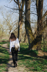 A girl with a backpack is walking down the path alone, women walking through the park