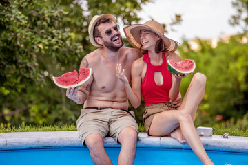 Fototapeta na wymiar Lovely couple eating watermelons by poolside.