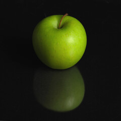 Green apple and reflection on black background