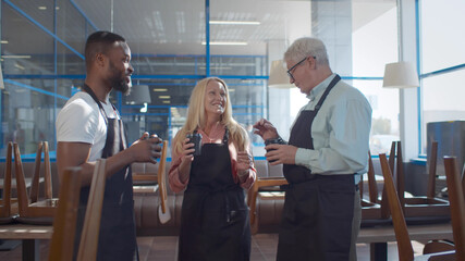 Diverse cafe workers have business conversation while standing with coffee at cafe