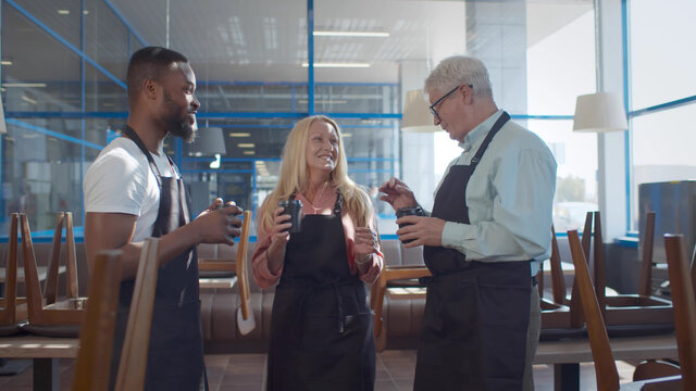 Diverse cafe workers have business conversation while standing with coffee at cafe - Powered by Adobe