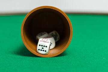 Playing poker dice closeup on a cup with green background